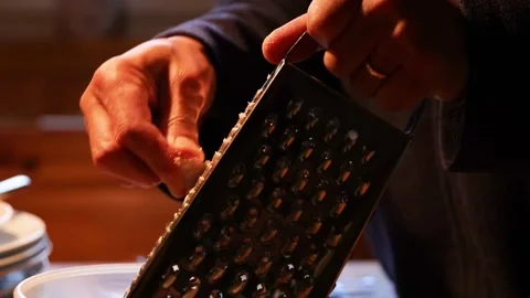 Man is rubbing parmesan into a plastic bawl on a wooden table. Hands rub ch.. Stock-Footage 277456943