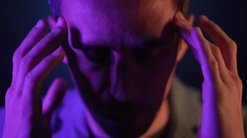 Man Rubbing Temples Under Neon Light in Focused Contemplation 스톡 동영상 312314157