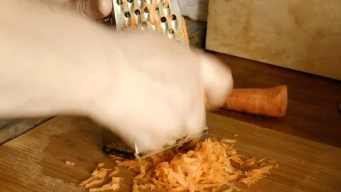 Man rubs carrots on a grater Stock Footage
