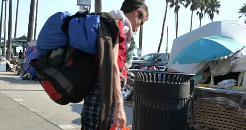 Man rummaging through trash at a homeless encampment on Venice Beach Stock Footage