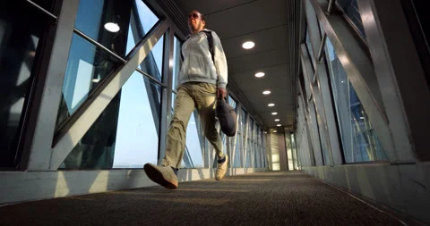 Man run through passenger boarding bridge to terminal, low angle slowmo shot Stock Footage 319011676