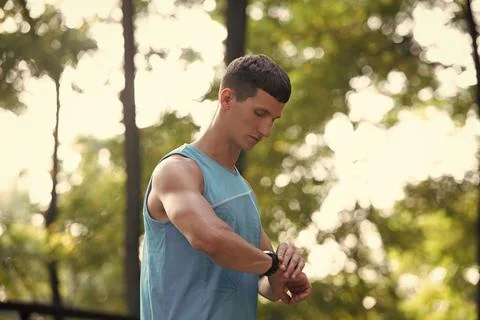 Man runner in activewear checking time on tracker Stock Photos