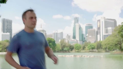 Man runner jogging in park. Fit male sport fitness running training. Talking on Stock Footage 74434106