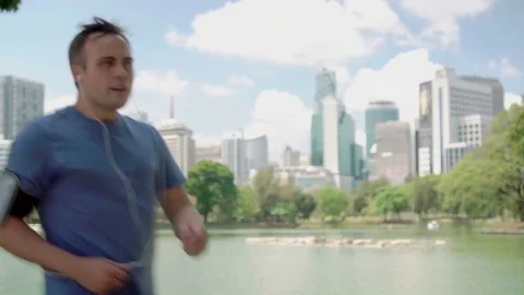 Man runner jogging in park. Fit male sport fitness running training. Listen Stock Footage 74434201