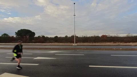 Man running across an empty road at sunrise - Side view. Stock Footage 336097530