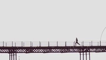 Man running along a British town pier, on seaside beach front  Stock Footage 85657243