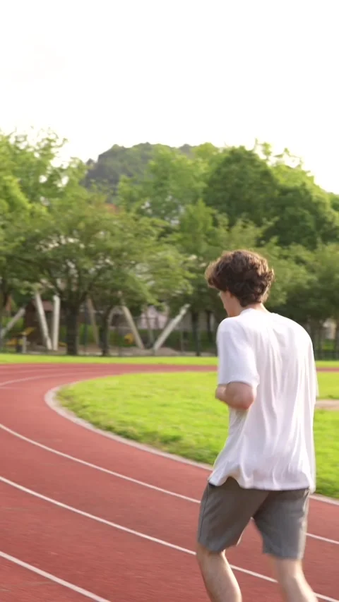 Man running along an outdoor running track during sunset Stock Footage 299896599