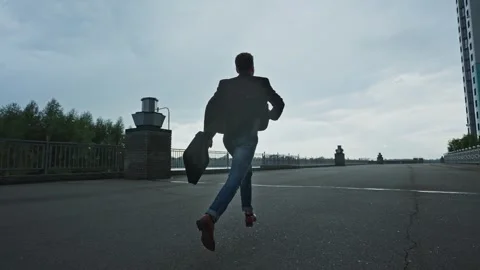 Man running along a waterfront path during cloudy weather in the evening 스톡 동영상 303799050