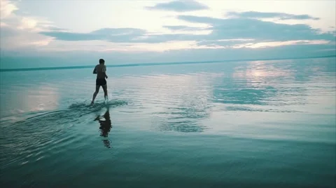 Man running and jumping on the river on sunset 스톡 동영상 68935025