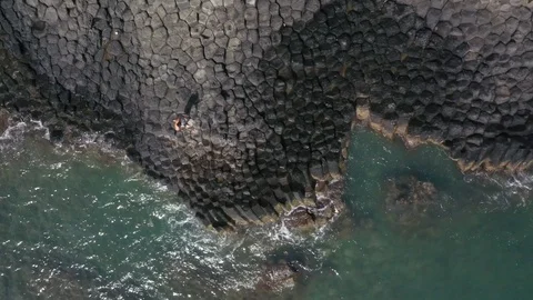 Man Running on Basalt Columns Along Ocean Top Down Aerial Drone Shot Stock Footage 122239204