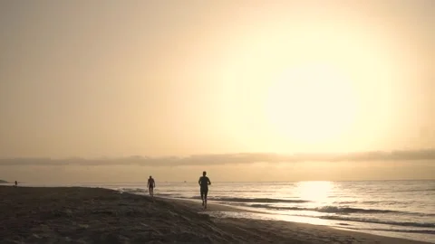 Man is running on the beach as the sun rises over the ocean Stockbeeldmateriaal 293157961