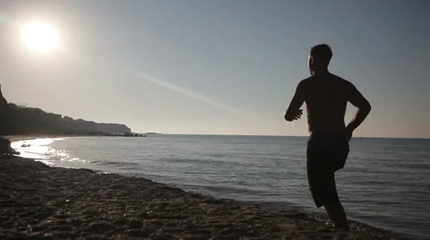 Man running on beach at sunrise. Video stock 66798140