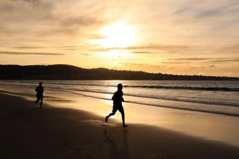 Man running on the beach at sunset Stock Photos