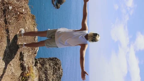 A man running to the cliff edge and spreading his hands Stock Footage 205516385