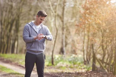 Man Running In Countryside Exercising Checking Smart Watch Fitness Activity App Stock Photos