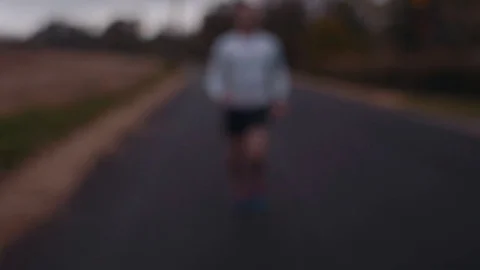 Man Running Down Autumn Road (Rack Focus) Stock Footage 81529937