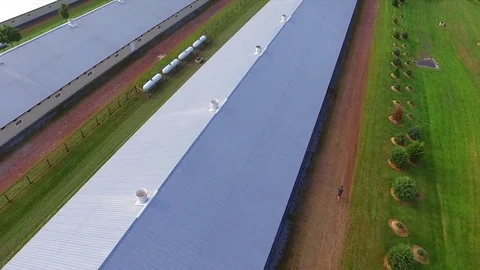 Man Running Down Dirt Road Alongside Large Warehouse Building in the Country 스톡 동영상 71325447