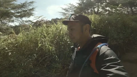Man running down the mountain wearing a jacket, hat and glasses holding a camera Stockbeeldmateriaal 152786624