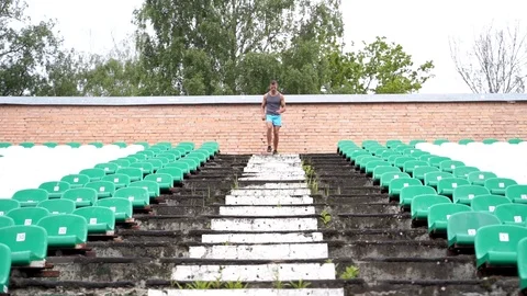Man running down stadium stairs between seats in slow motion Stock Footage 114089679