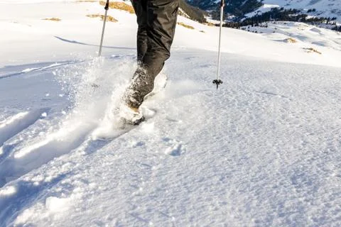 Man running downhill through deep snow with snoeshoes and hiking sticks. Stock-Fotos