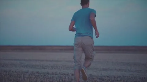 Man running at evening field HD slow motion video. Farm rural twilight landscape Stock Footage 68583613