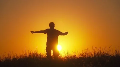 Man running in the fields towards setting sun, spreading his hands, slow motion. Stock Footage 55098773