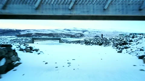 A man running on the frozen river bridge in winter of Hengifoss waterfall Stock Footage 281315723