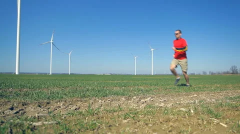 Man running on green field with wind turbines Stock Footage 61482205