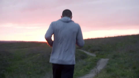 Man running in hilly countryside at sunset Stock Footage 153565649