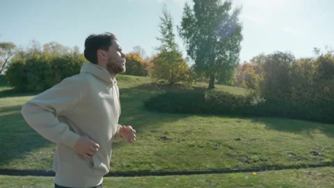 Man running on jogging track at the city park in sunny autumn morning, side view 스톡 동영상 163714092