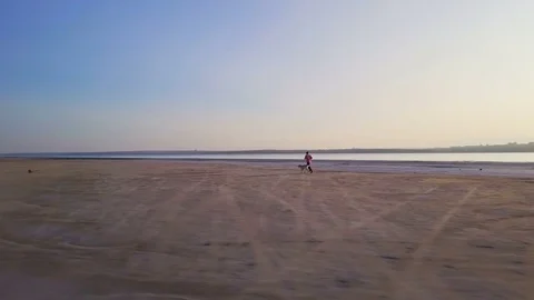 Man running with labrador dog at empty beach seaview sundown drone footage Stock Footage 79775080