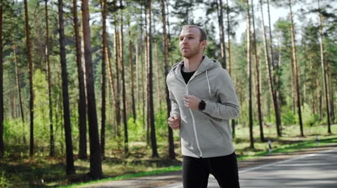 Man running looking at his pulse outside in nature on road with smartwatch. Stock Footage 63057705