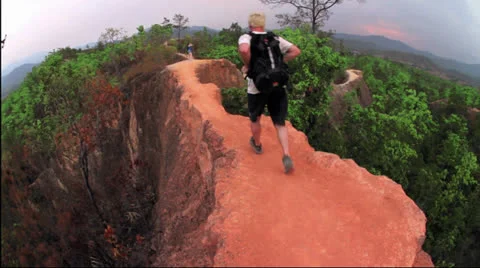 Man running narrow trail wearing backpack in Pai canyon Stock Footage 24268331