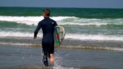 Man running into ocean for surf lesson Stock Footage 336613728
