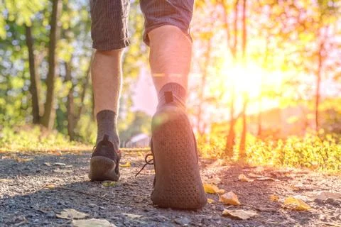 Man is running or walking at sunset. View on legs and feet from behind. Stock Photos