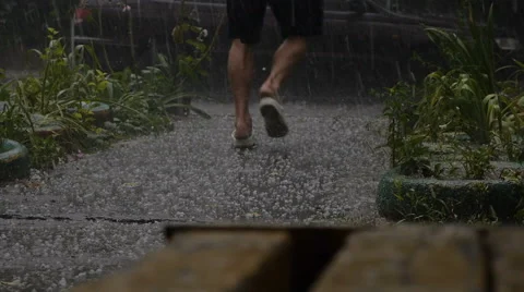 Man Running out of the Heavy Rain on Asphalt Road. Static Shoot Stock Footage 68538465