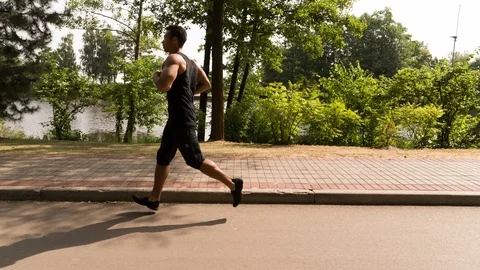 Man running in Park sunny day Follow shot Side view video Stock Footage 112145228