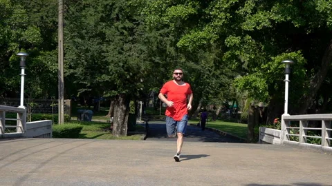 Man running on pavement in the park, slow motion shot at 240fps  Stock Footage 90561394