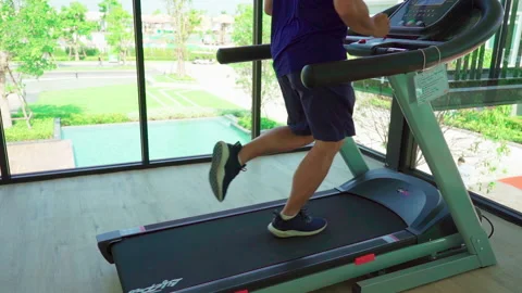 Man running on the running machine see garden view slow motion Video stock 158674741