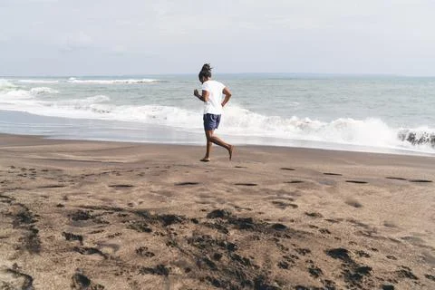Man running on sandy seashore Stock Photos