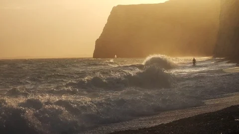 Man running on the seashore with waves crushing in the jurassic coast Stock Footage 124908394