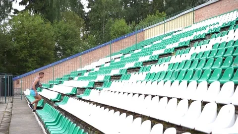 Man running up stadium stairs between seats in slow motion Stock Footage 114089396