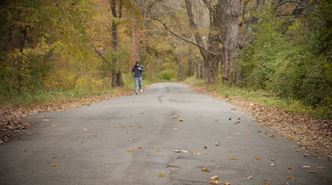 Man running  through Autumn foliage Stock Footage 32165741