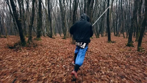 Man running through a forest carrying a large sword, dodging trees and Stock Footage 102970010