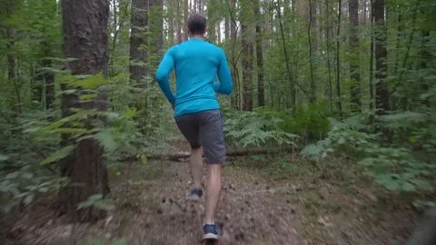 Man running through forest jumping over fallen trees, overcoming obstacles Stock Footage 116910694