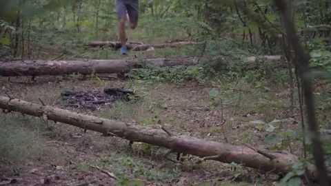 Man running through forest jumping over fallen trees, overcoming obstacles Stock Footage 117066467