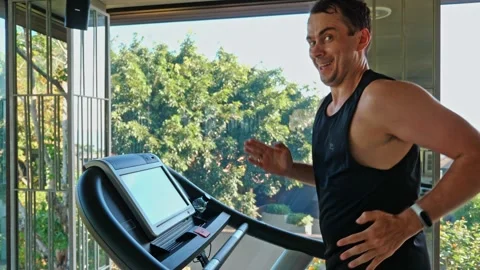 Man running on treadmill in gym looking at camera and smiling Видео 335468627