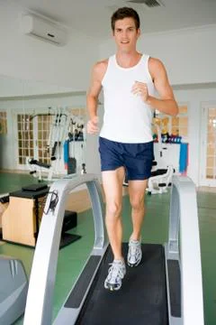 Man running on treadmill at gym Photos