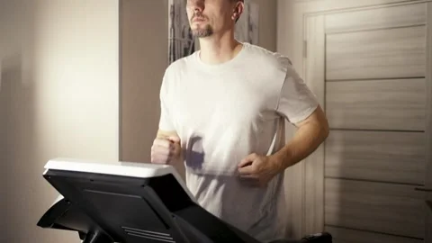 Man running on a treadmill at home. Middle-aged man in a grey t-shirt exerc.. Stock Footage 332162038