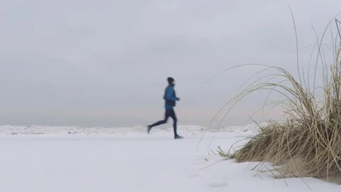 A man running in winter on a snowy beach with a dog 動画素材 85399809